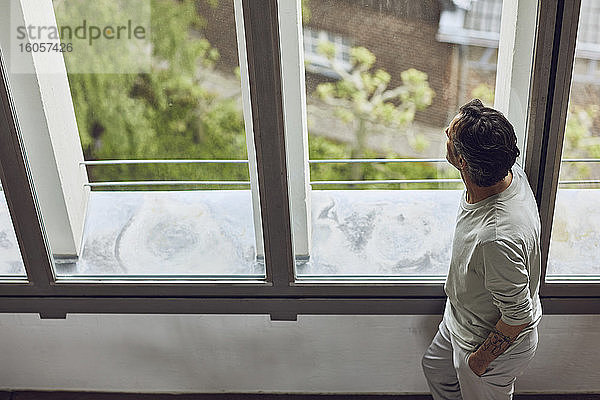 Älterer Mann schaut aus dem Fenster in einer Dachgeschosswohnung