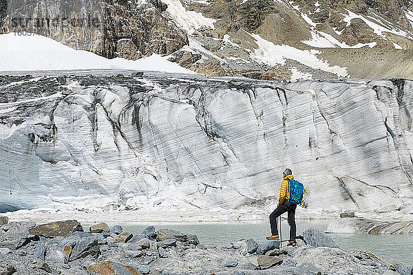 Älterer männlicher Wanderer mit Blick auf den schmelzenden Gletscher