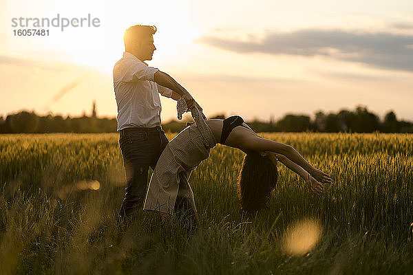 Tanzendes Paar auf einem Feld bei Sonnenuntergang