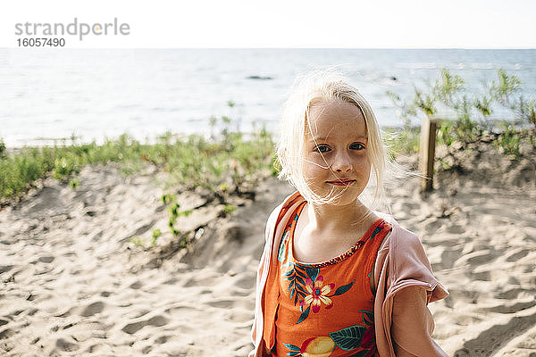 Blondes Mädchen steht am Strand gegen Georgian Bay an einem sonnigen Tag