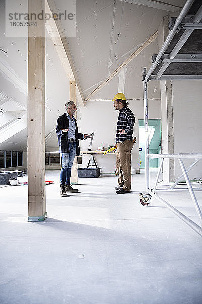 Architekt und Bauarbeiter planen im Stehen beim Bau eines Hauses