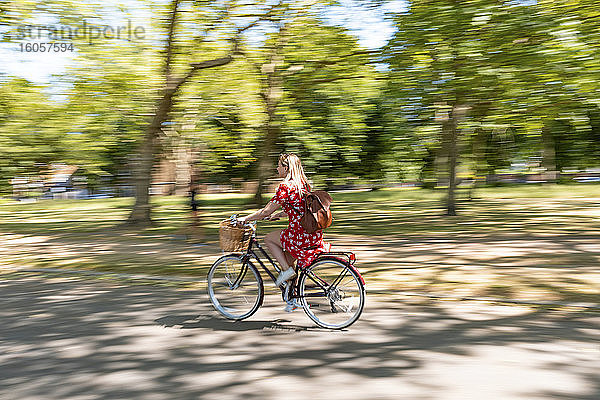 Unscharfe Bewegung einer Frau beim Fahrradfahren auf dem Fußweg im Park