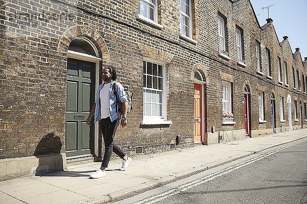 Junger Mann geht auf dem Bürgersteig vor einem Wohnhaus  London  UK