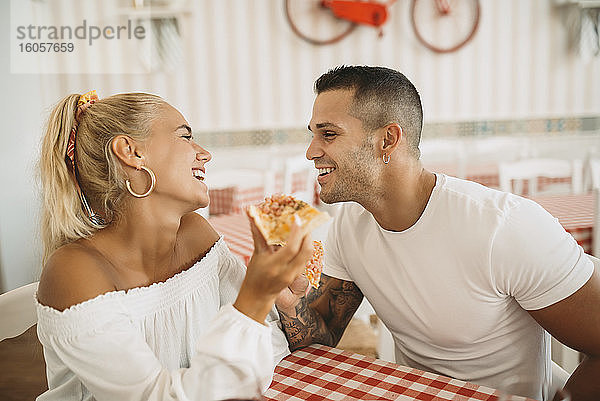 Glückliches junges Paar  das im Restaurant sitzt und Pizza isst