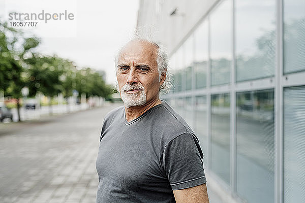 Selbstbewusster älterer Mann  der an einem Gebäude in der Stadt steht