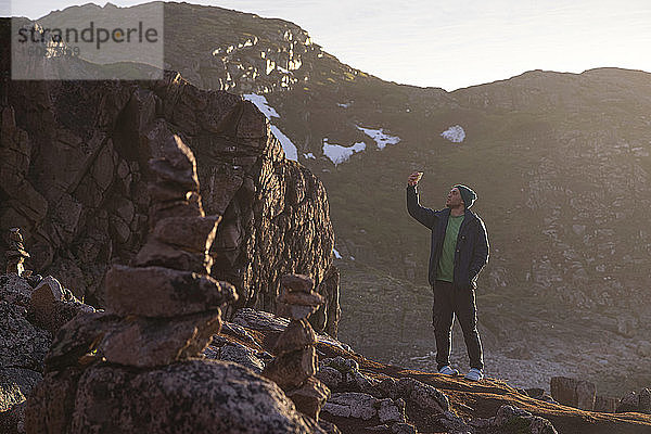 Mann  der ein Selfie macht  während er auf einem felsigen Berg in Teriberka steht  Gebiet Murmansk  Russland