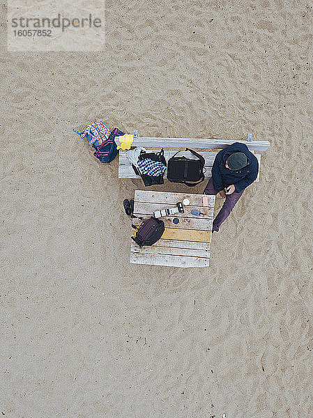 Luftaufnahme eines Mannes  der sich auf einer Bank am Strand entspannt