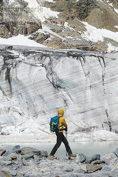 Älterer Mann erforscht schmelzenden Gletscher  während er auf Felsen steht