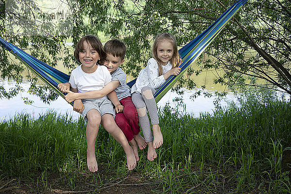 Fröhliche Freunde sitzen in einer Hängematte im Wald