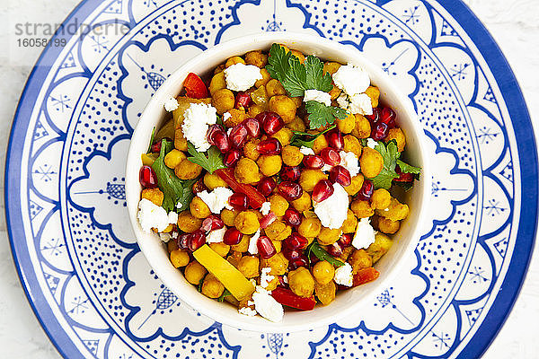 Schüssel mit vegetarischem Salat mit Kichererbsen  Kurkuma  Paprika  Tomaten  Petersilie  Feta-Käse und Granatapfelkernen