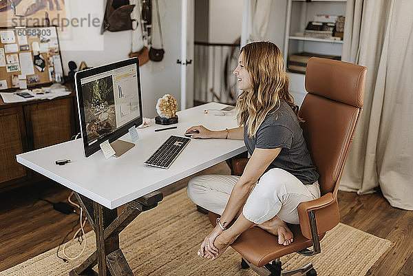 Frau mit Computer auf dem Schreibtisch zu Hause