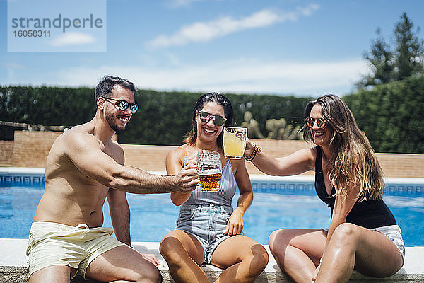 Freunde stoßen auf einer Poolparty mit Bier an
