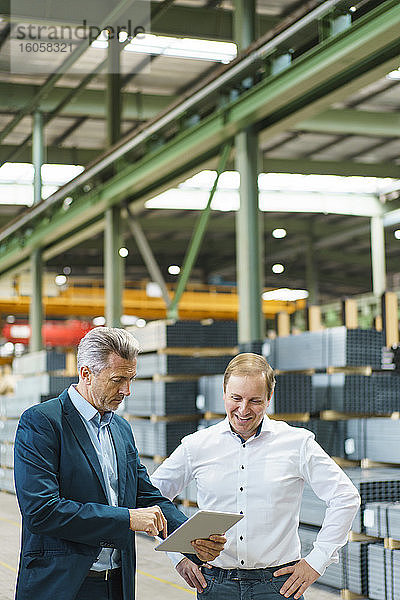 Zwei Geschäftsleute benutzen ein Tablet in einer Fabrik