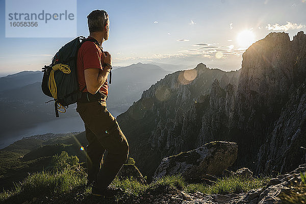 Männlicher Wanderer mit Rucksack mit Blick auf die Berge bei Sonnenuntergang  Orobie  Lecco  Italien