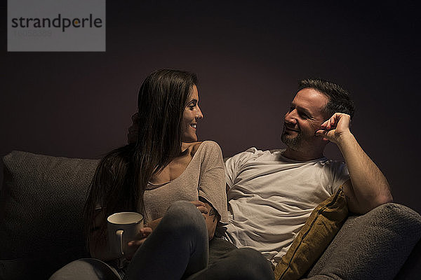 Glückliches Paar  das sich gegenseitig ansieht  während es sich auf dem Sofa zu Hause entspannt