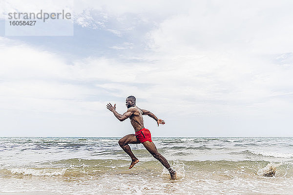 Sportlicher Mann läuft am Strand