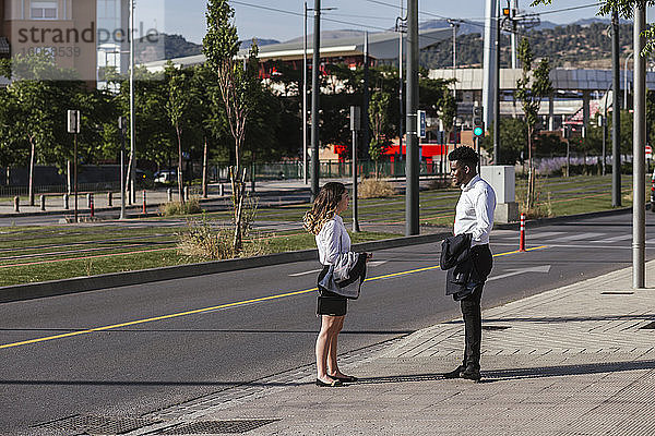 Geschäftsleute diskutieren auf dem Bürgersteig in der Stadt an einem sonnigen Tag
