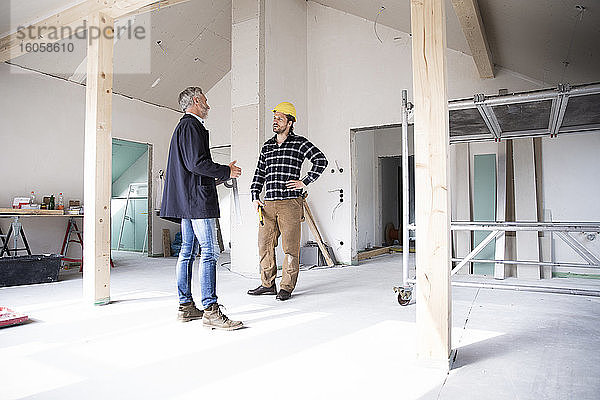 Architekt und Bauarbeiter diskutieren im Stehen bei der Renovierung eines Hauses