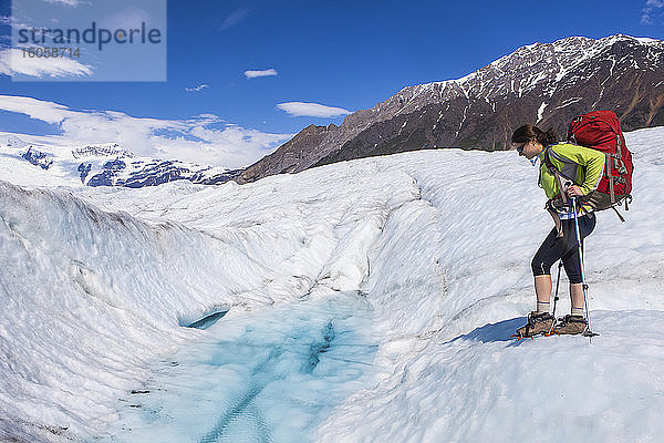 Rucksacktour einer Frau über den Root Glacier mit Steigeisen im Sommer  Wrangell Mountains  Wrangell-St.-Elias-Nationalpark  Süd-Zentral-Alaska; Kennicott  Alaska  Vereinigte Staaten von Amerika