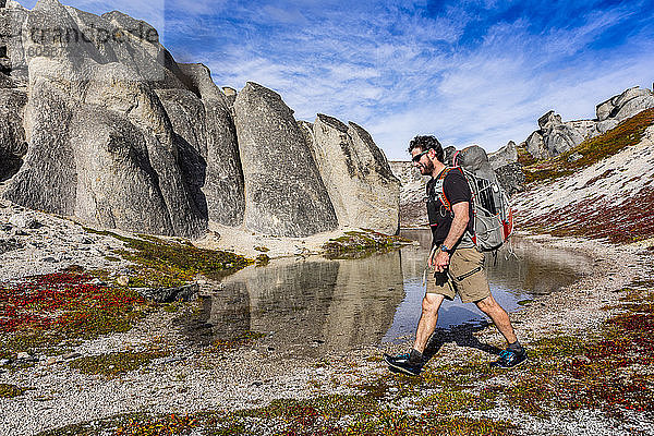 Mann auf Rucksacktour am Teich und an riesigen Felsen vorbei auf dem Kesugi Ridge Trail  Denali State Park  Alaska an einem sonnigen Herbsttag  Süd-Zentral-Alaska; Alaska  Vereinigte Staaten von Amerika