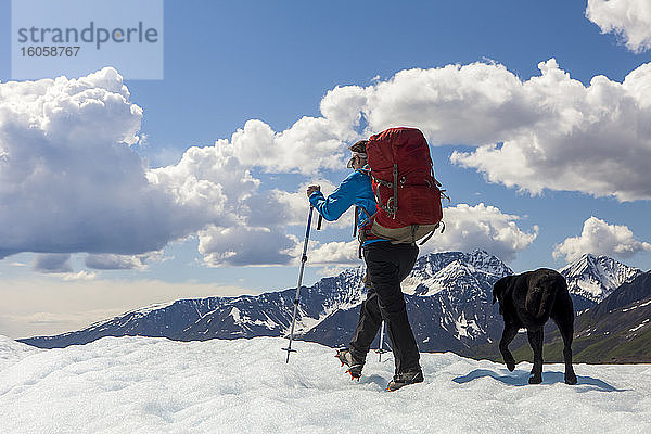 Frau und ihr Hund mit Rucksack auf dem Kennicott Glacier  Wrangell Mountains  Wrangell-St.-Elias-Nationalpark  Süd-Zentral-Alaska; Alaska  Vereinigte Staaten von Amerika