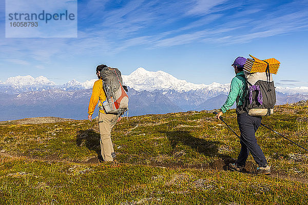 Frau und Mann mit Rucksack auf der Tundra in Richtung Denali und Alaska Range  entlang des Kesugi Ridge Trail  Denali State Park  an einem sonnigen Herbsttag  Süd-Zentral-Alaska; Alaska  Vereinigte Staaten von Amerika