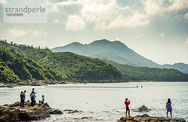 Menschen  die an einem ländlichen Strand auf einer Insel in Hongkong vor einem gebirgigen Hintergrund fotografieren; Lamma Island  Sonderverwaltungsregion (SAR) Hongkong  China