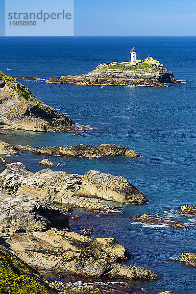 Weißer Godrevy-Leuchtturm auf einer Felsformation im blauen Wasser mit blauem Himmel und felsiger Küstenlinie  Godrevy Island in der St. Ives Bay; Grafschaft Cornwall  England