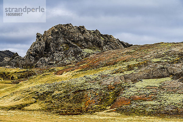 Zerklüftete Felsvorsprünge und farbenfrohe Tundra an einem Hang; Island