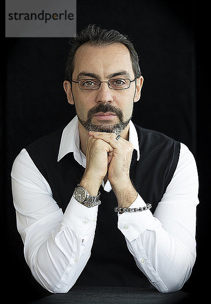 Porträt eines angesehenen Mannes mit Gesichtsbehaarung und Brille vor schwarzem Hintergrund; Atelier