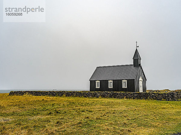 Kirchengebäude mit Kirchturm und Kreuz in einer abgelegenen Gegend mit Steinmauer und Gras; Snaefellsbaer  Westliche Region  Island