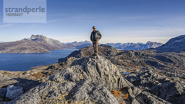 Ein Mann blickt aus der zerklüfteten Landschaft an der grönländischen Küste heraus; Sermersooq  Grönland