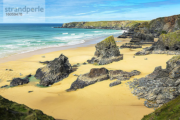 Sandstrand mit Felsformationen entlang einer felsigen Kliffküste mit Brandung und blauem Himmel und Wolken; Cornwall County  England