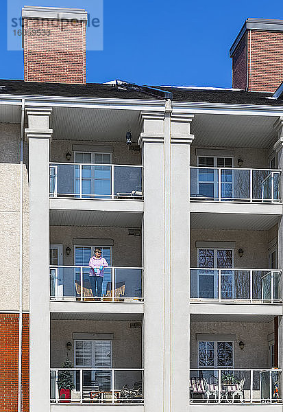 Eine Frau steht auf ihrem Balkon und holt während der Isolation frische Luft  Covid-19 Weltpandemie; St. Albert  Alberta  Kanada
