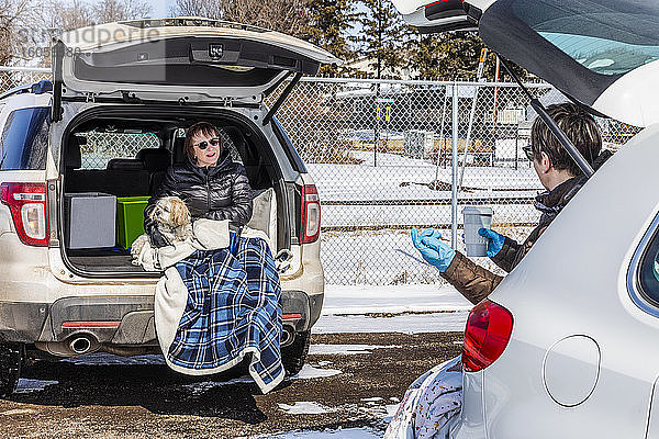 Zwei Frauen sitzen hinten in ihren Fahrzeugen auf einem Parkplatz  den sie während der Weltpandemie Covid-19 besuchen; St. Albert  Alberta  Kanada