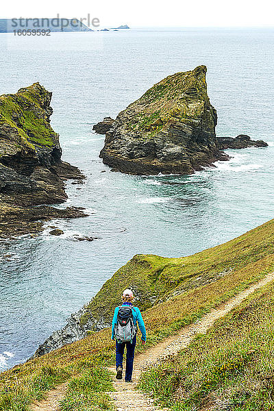 Wanderin  die eine Steintreppe mit Felsformationen entlang einer Klippenküste hinuntergeht; Cornwall County  England
