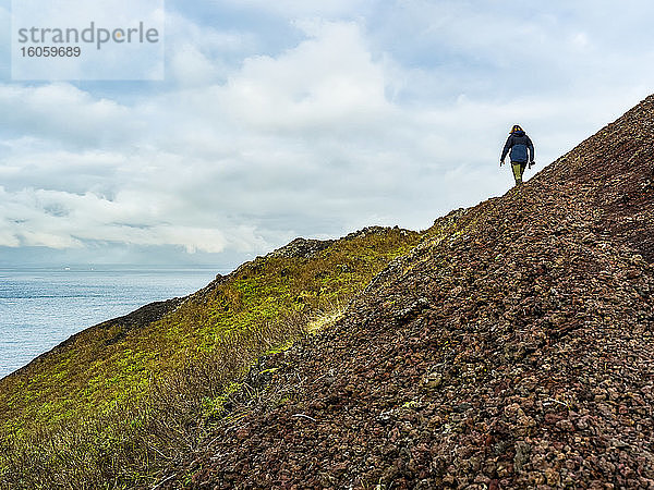 Wanderer wandert entlang eines Bergrückens in Südisland; Vestmannaeyjar  Südliche Region  Island