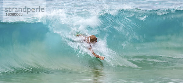 Ein Mann schwimmt im Kamm einer türkisfarbenen Welle; Kihei  Maui  Hawaii  Vereinigte Staaten von Amerika