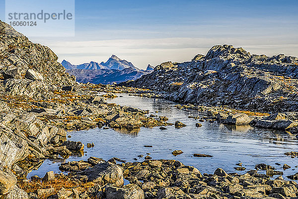 Felsige Landschaft mit Wasser und schroffen Berggipfeln in der Ferne; Sermersooq  Grönland