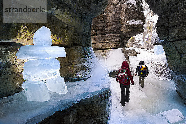 Zwei Personen erkunden im Winter einen Canyon mit Eisblock inukshuk  Jasper National Park; Alberta  Kanada
