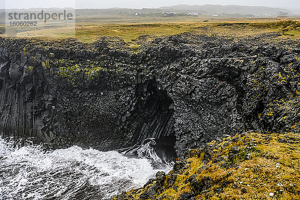 Aussichtspunkt von einer Klippe zu den Wellen  die in eine vulkanische Höhle entlang der Küste in Arnarstapi rollen; Snaefellsbaer  Westliche Region  Island