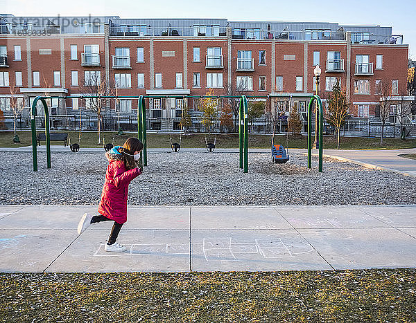 Junges Mädchen spielt auf einem Spielplatz Himmel und trägt eine Schutzmaske zum Schutz vor COVID-19 während der Coronavirus-Weltpandemie; Toronto  Ontario  Kanada