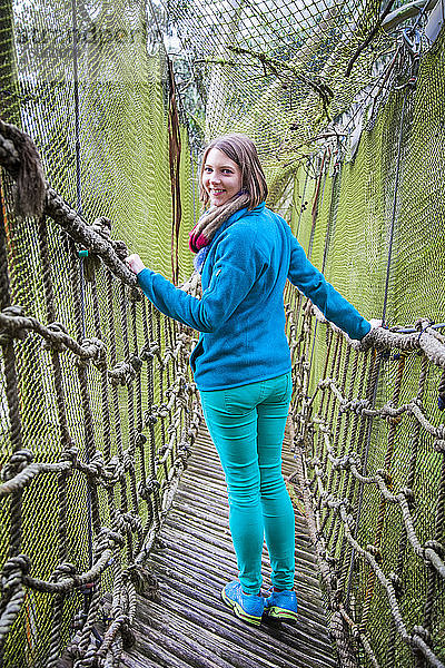 Frau geht auf einer Seil- und Holzbrücke mit Netzen im ecuadorianischen Waldbaumfort; Calicali  Ecuador