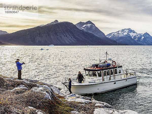 Touristen mit ihrem Ausflugsboot entlang der zerklüfteten Küstenlinie  die ihr Ausflugsboot und die Landschaft fotografieren; Nuuk  Sermersooq  Grönland