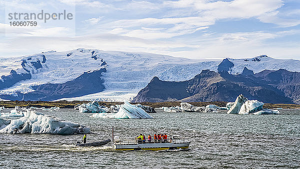 Ausflugsboot im Gletschersee  Jokulsarlon  Vatnajokull-Nationalpark. Die Gletscherlagune fließt durch einen kurzen Wasserweg in den Atlantischen Ozean und hinterlässt Eisbrocken an einem schwarzen Sandstrand; Hornafjordur  östliche Region  Island