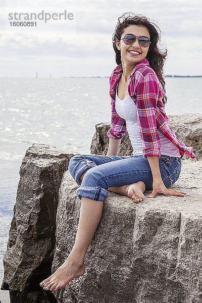 Teenager-Mädchen sitzt auf Felsen und schaut auf den See  Woodbine Beach; Toronto  Ontario  Kanada