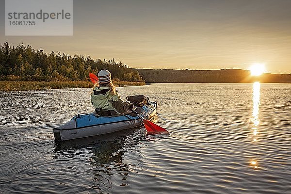 Kajakerin  Ende vierzig  blond  paddelt mit aufblasbarem Kajak bei Sonnenuntergang auf einem See in Abendstimmung  Muddus Nationalpark  Jokkmokk  Norrbottens län  Schweden  Europa
