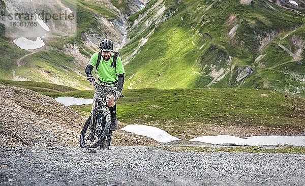 Mountainbiker mit Helm  Anfang fünfzig fährt auf alpiner Schotterstraße  Serfaus  Tirol  Österreich  Europa