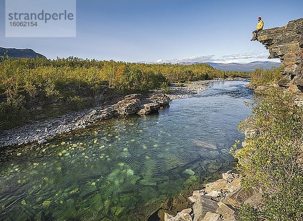 Mann sitzt auf Steinklippe über dem Fluss Abiskojåkka  Abisko Nationalpark  Lappland  Abisko  Norrbottens län  Schweden  Europa