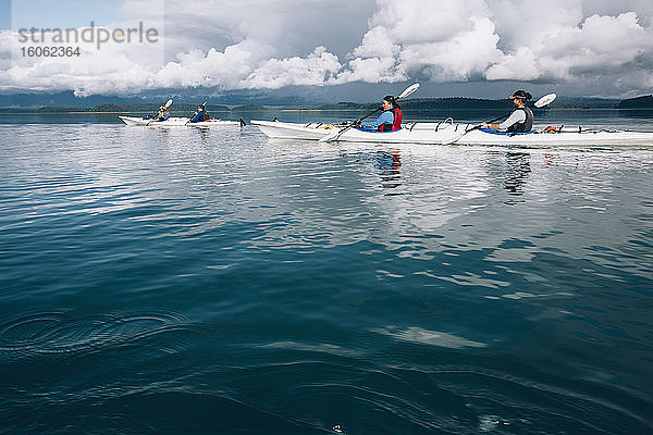 Seekajakfahrer paddeln in unberührten Gewässern einer Bucht an der Küste Alaskas.